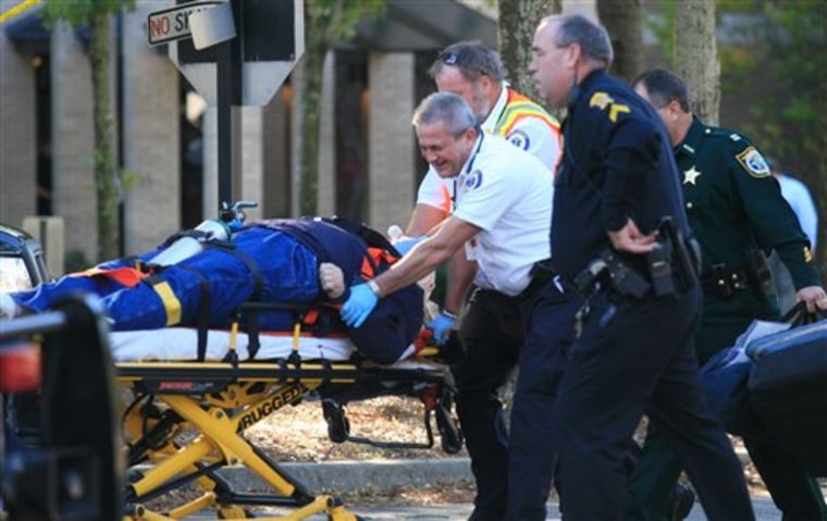 Paramedics transport a gunman who was shot dead after he disrupted a Bay District School Board meeting in Panama City, Fla., on Tuesday, Dec. 14, 2010. Police say the gunman calmly went to the podium to speak to the board, spray painted the wall behind him, and waved a handgun. A school safety officer, Mike Jones, responded and shot Duke twice. (AP Photo/The News Herald, Robert Cooper)